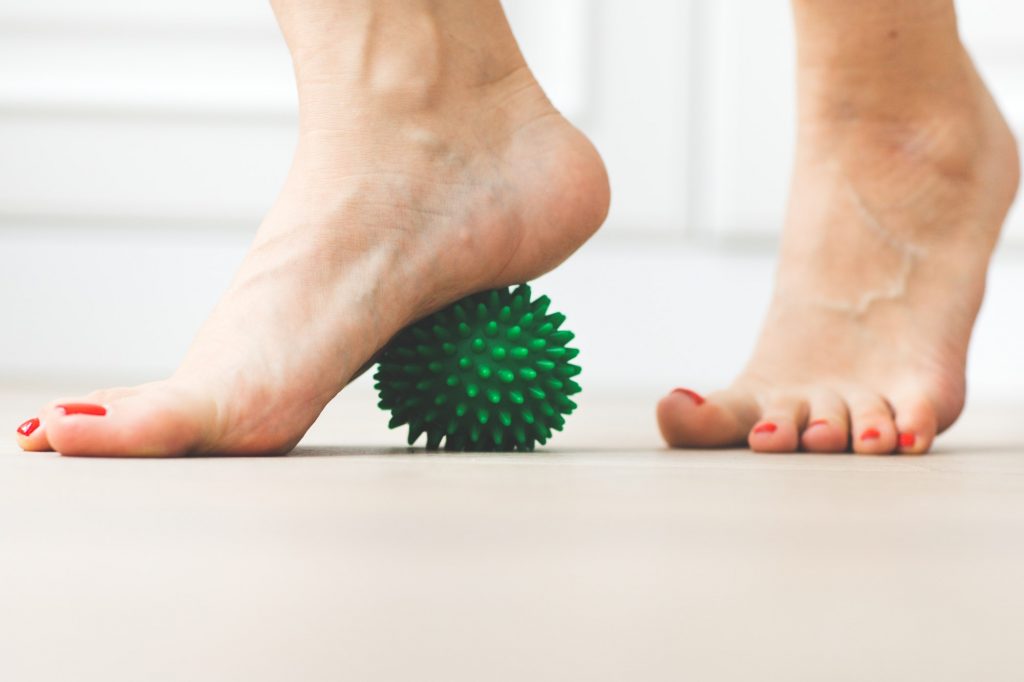 woman bare feet and green massage ball physical therapy and massage